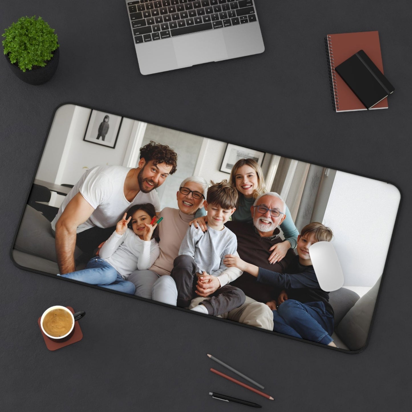 Desk pad 16 x 32 Personalized mouse pad with a family photo on a dark surface with office items.