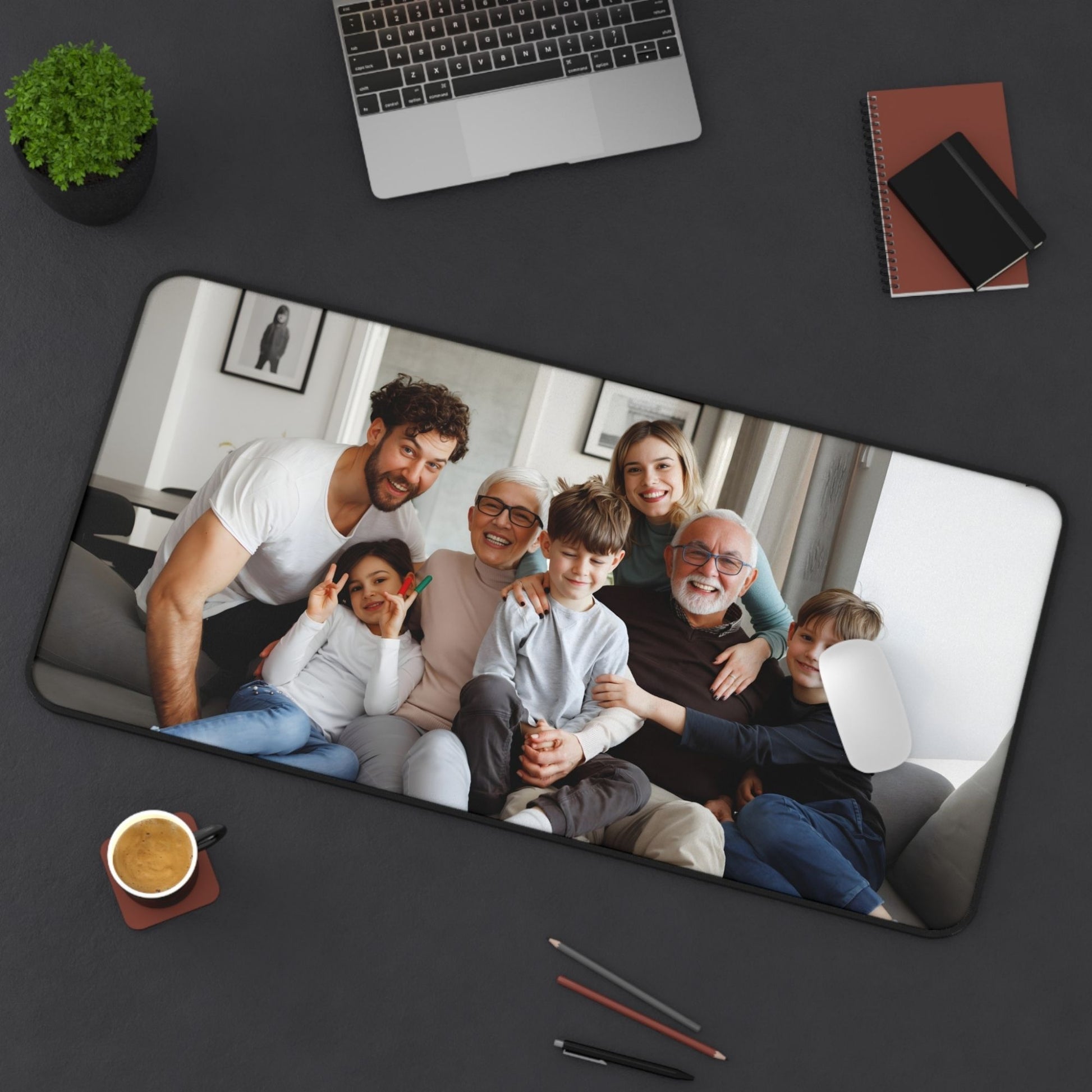 Desk pad 16 x 32 Personalized mouse pad with a family photo on a dark surface with office items.